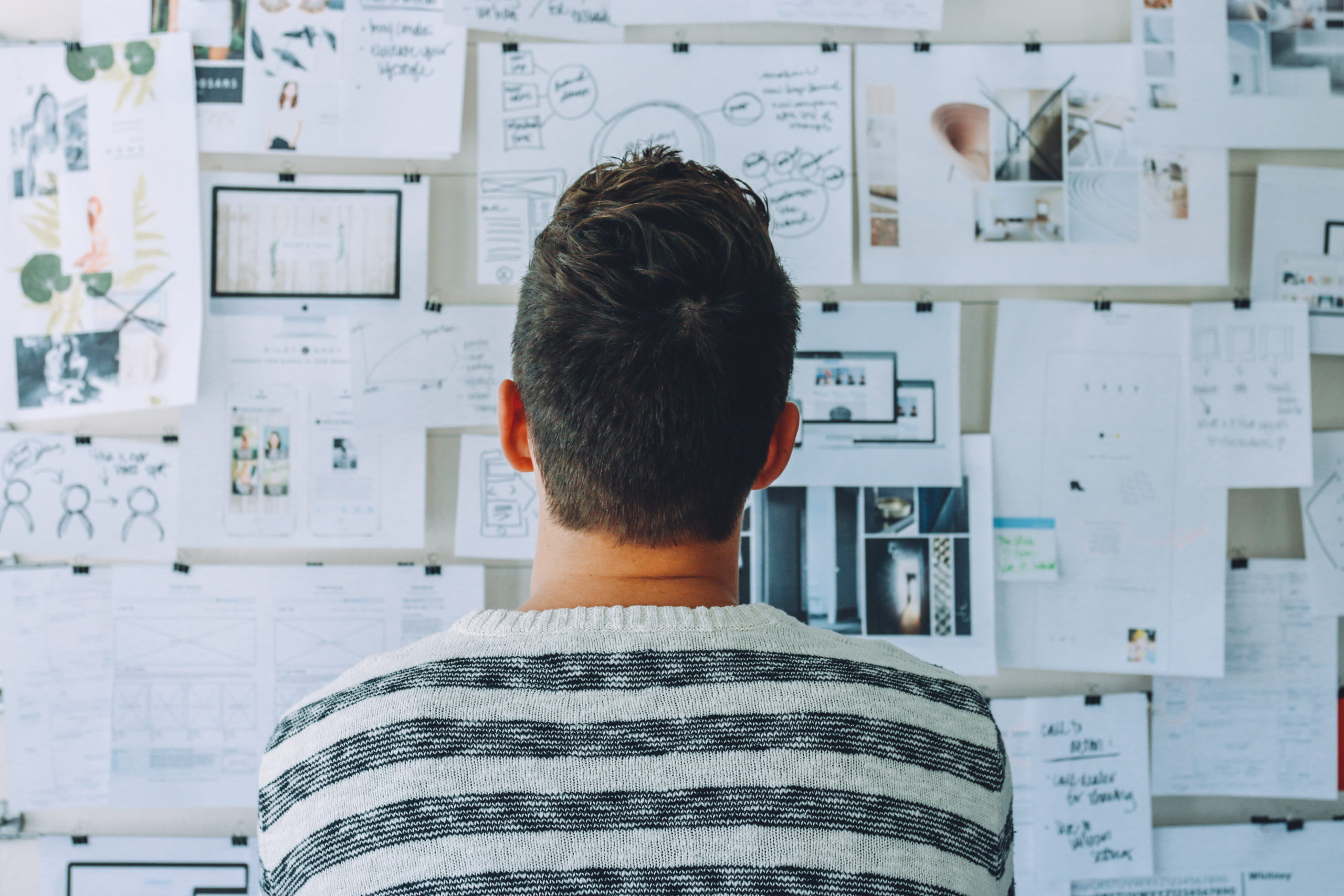 Man Looking at White Printer Papers on the Wall